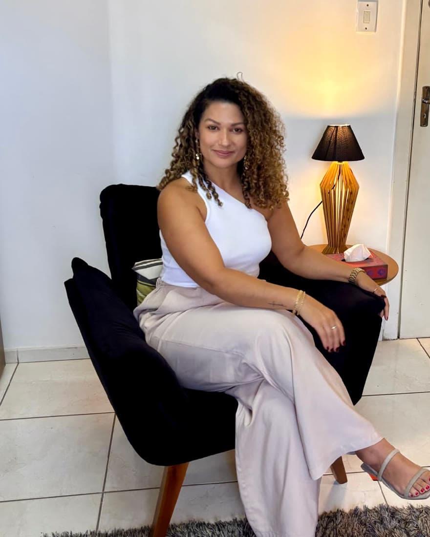 Karla França no consultório, sentada em uma poltrona